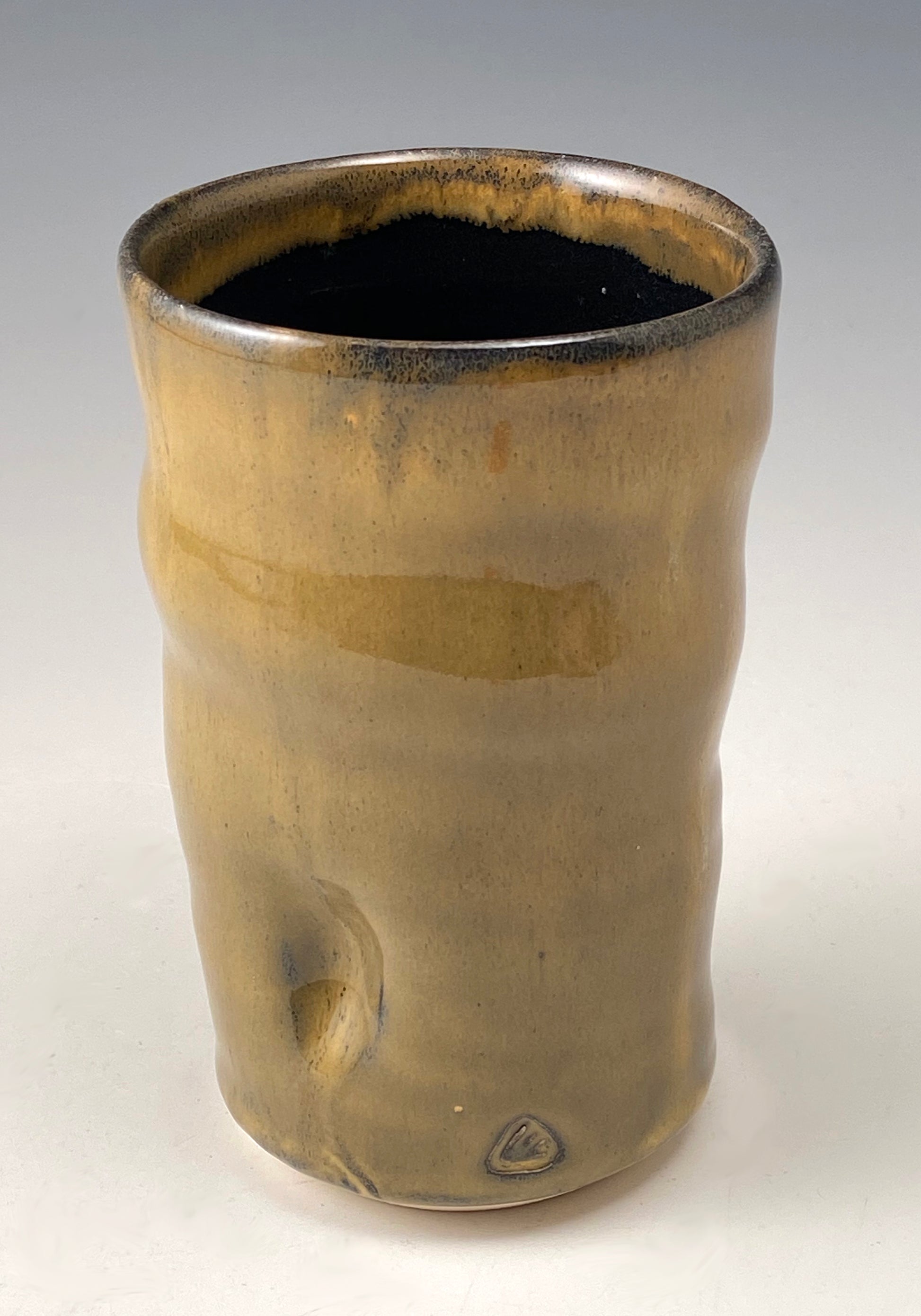 Handmade Pottery.  Stoneware cup with amber-colored glaze on exterior.  Black glaze on interior.