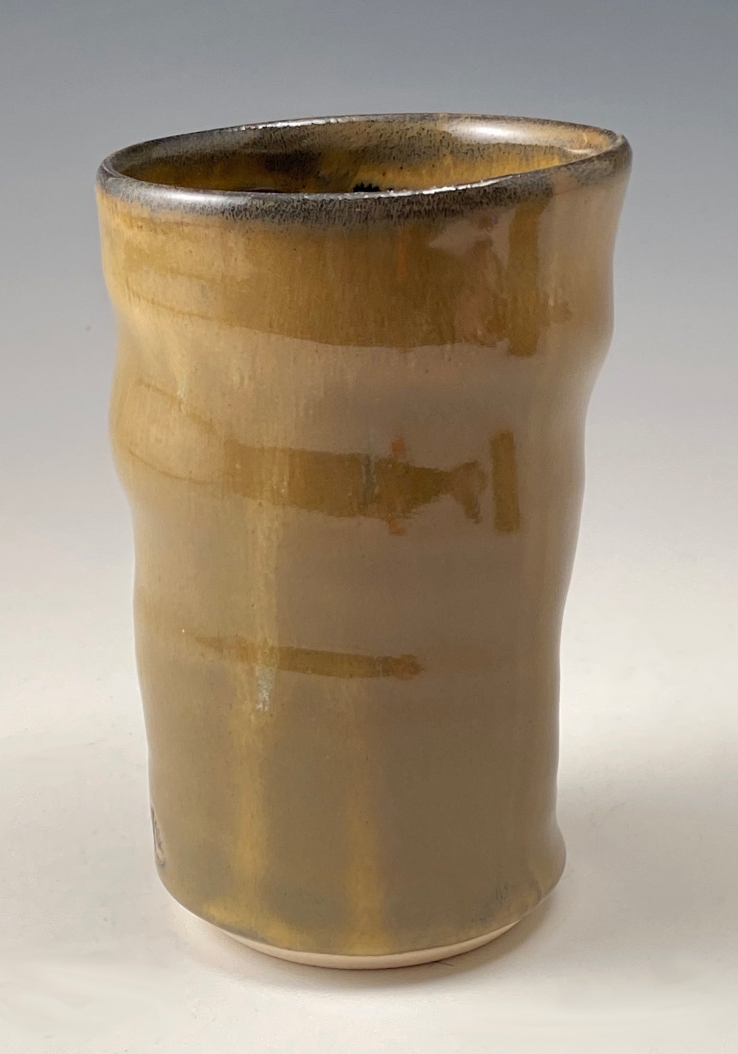 Handmade Pottery. Stoneware cup with amber-colored glaze on exterior. Black glaze on interior.