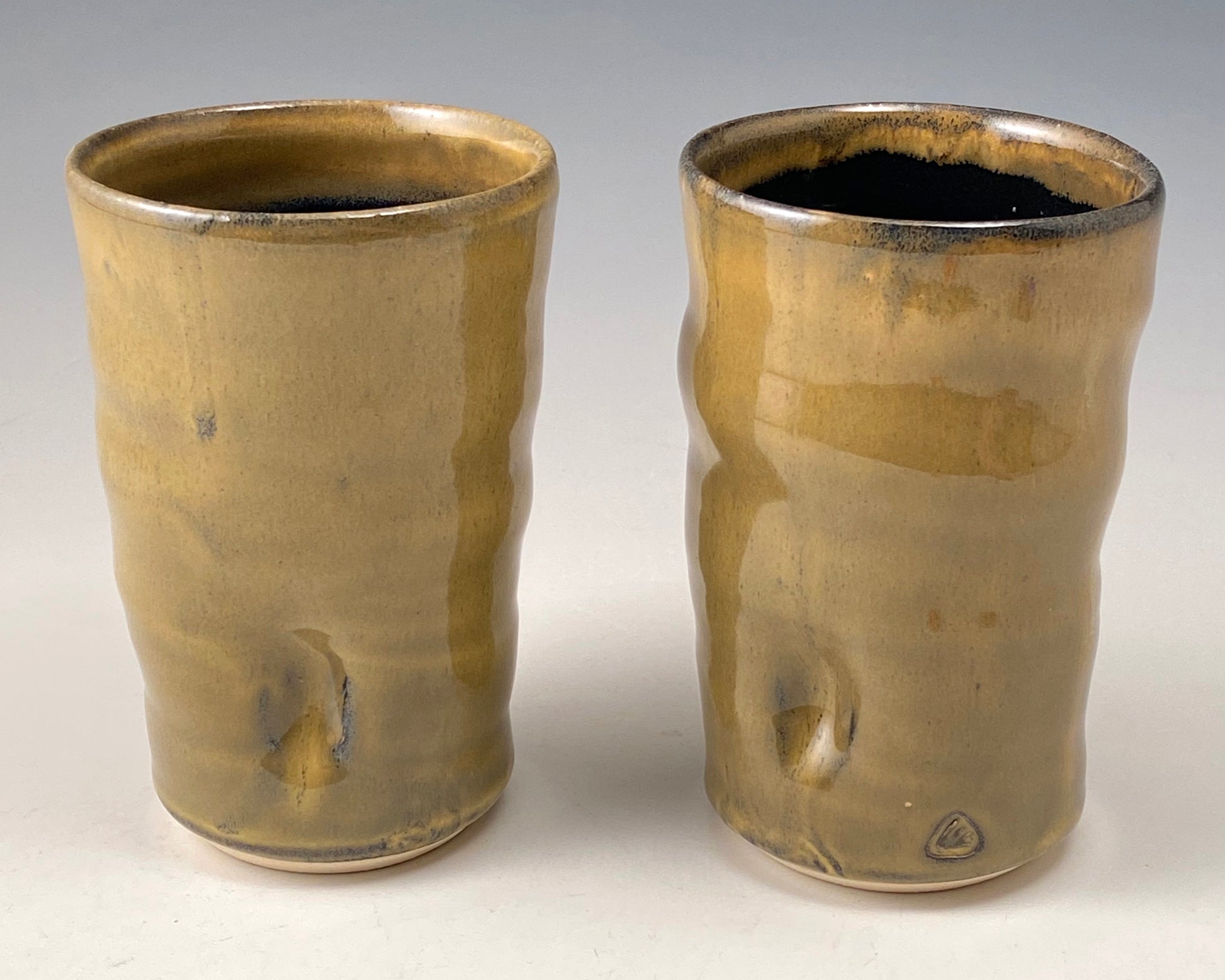Handmade Pottery. Stoneware cups with amber-colored glaze on exterior. Black glaze on interior.