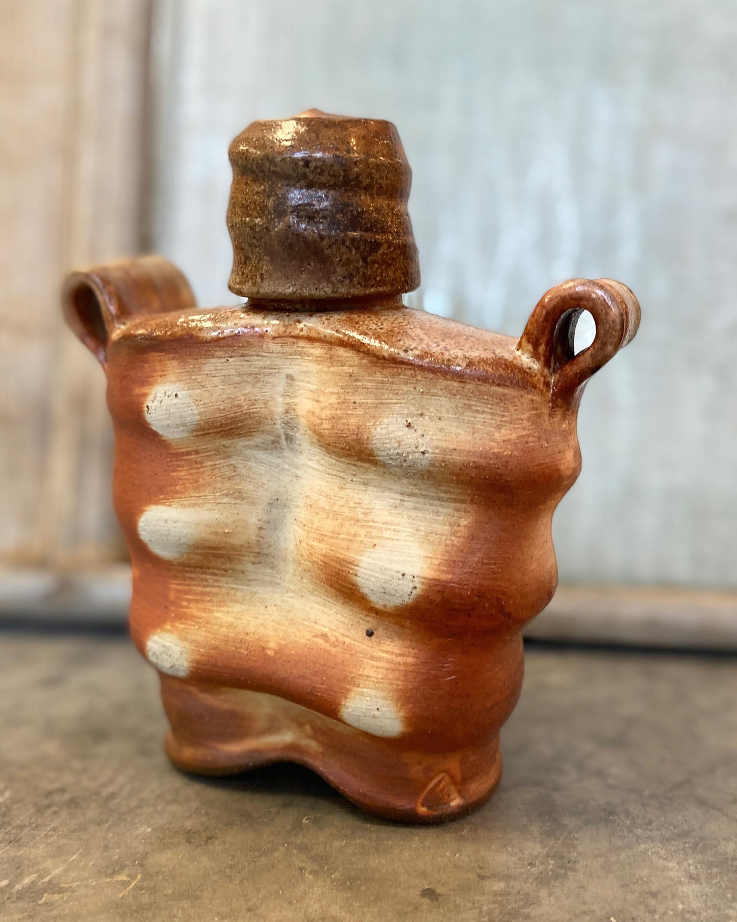 Wood-fired stoneware whiskey flask with liner glaze. Handmade Pottery.  Unique design, yet functional. 7" tall. 6" wide.  3" deep.