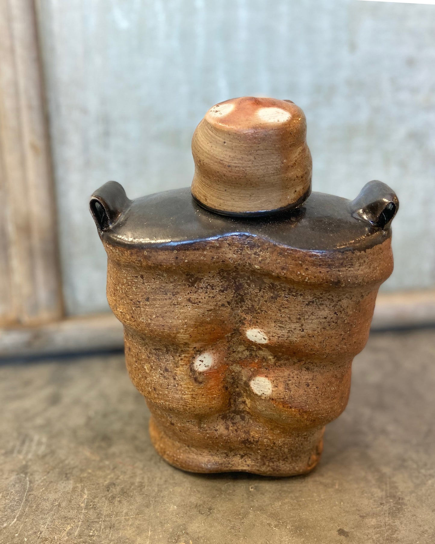 Wood-fired Stoneware Whiskey Flask with black liner glaze and black shoulders. Handmade. One-of-a-kind ceramic flask. 7" tall. 5.5" wide. 3" deep.  View from above and back.