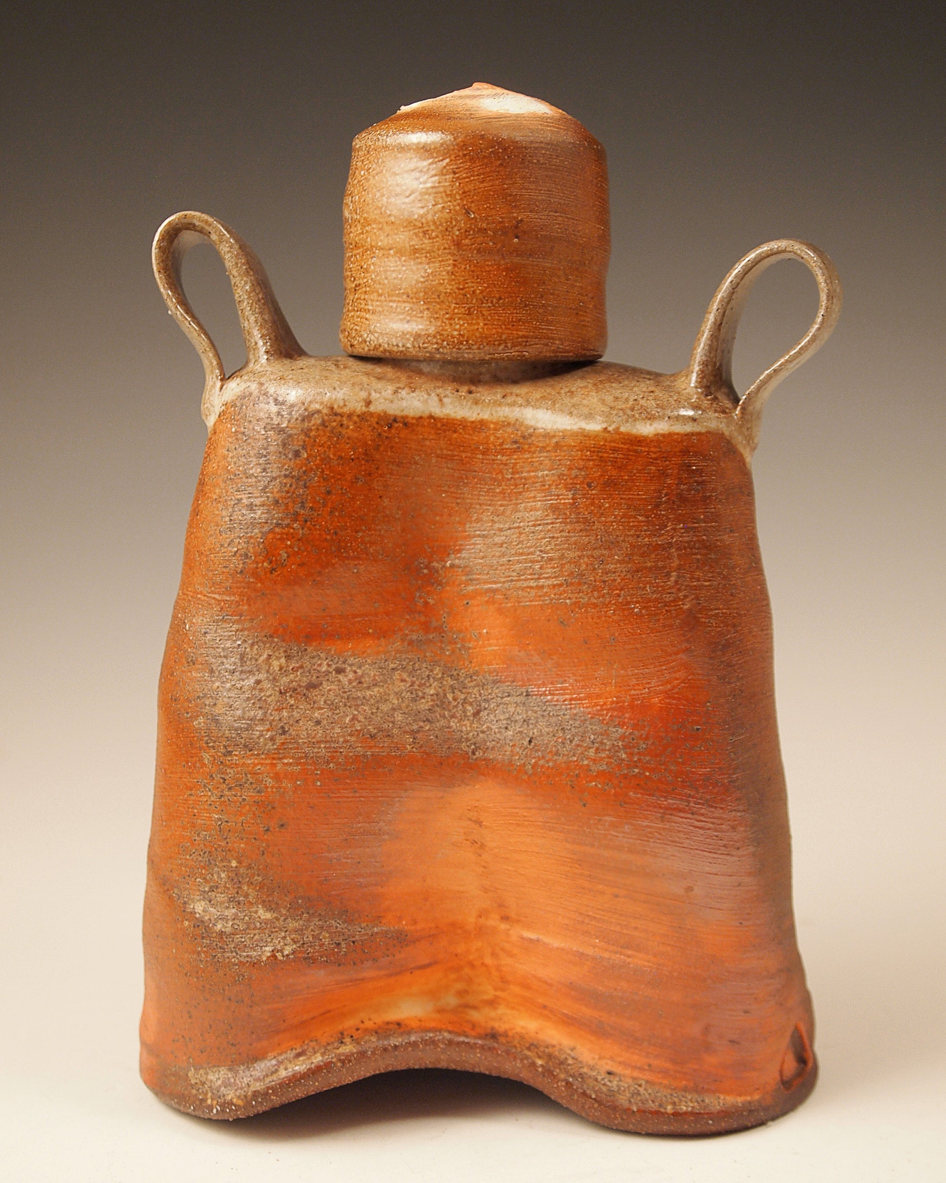 Small, handmade ceramic whiskey flask.  Wood-fired Stoneware.  Bright orange and brown slip exterior.  Rustic design.  Front view.